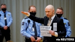 Mass killer Anders Behring Breivik, gestures while holding a sign, on the first day of the hearing, where he is requesting release on parole, at the makeshift courtroom in Skien prison, Norway January 18, 2022. NTB/Ole Berg-Rusten via REUTERS 