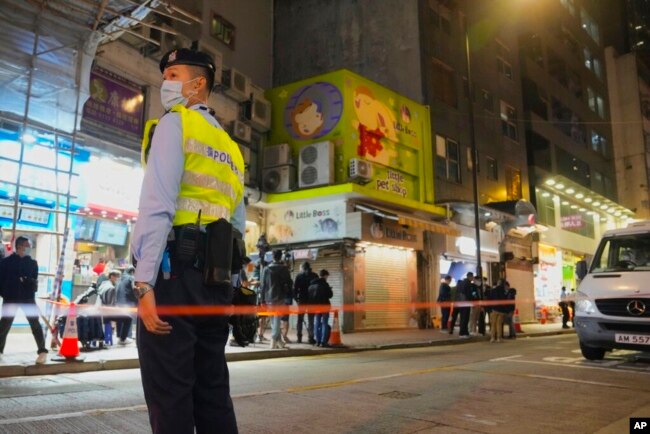 FILE - A police officer stands guard outside a pet store that was closed after some pet hamsters were, authorities said, tested positive for the coronavirus, in Hong Kong on Jan. 18, 2022.