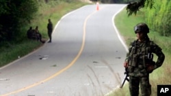 Un soldado del ejército colombiano hace guardia en el área donde un coche bomba fue encontrado y detonado por control remoto por el ejército después de ser abandonado por las FARC cerca de la ciudad de Caloto, suroeste de Colombia, el lunes 28 de marzo. de 2011.