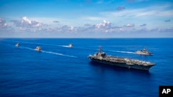 资料照片：2021年月19日美国航空母舰卡尔文森号、导弹巡洋舰尚普兰湖号和阿利伯克级导弹驱逐舰查菲号与日本海上自卫队舰艇在太平洋航行。