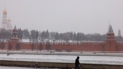 Un peatón camina a lo largo de un terraplén del río Moskva con el Kremlin al fondo durante una nevada en Moscú, el 21 de enero de 2022.
