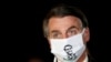FILE - Brazil's President Jair Bolsonaro speaks with journalists while wearing a protective face mask as he arrives at Alvorada Palace, amid the coronavirus disease (COVID-19) outbreak, in Brasilia, Brazil.