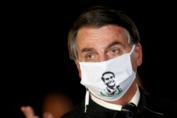 FILE - Brazil's President Jair Bolsonaro speaks with journalists while wearing a protective face mask as he arrives at Alvorada Palace, amid the coronavirus disease (COVID-19) outbreak, in Brasilia, Brazil.