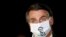 FILE - Brazil's President Jair Bolsonaro speaks with journalists while wearing a protective face mask as he arrives at Alvorada Palace, amid the coronavirus disease (COVID-19) outbreak, in Brasilia, Brazil.
