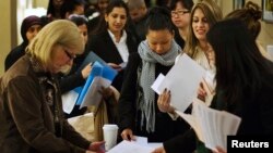 U.S. job seekers adjust their paperwork as they wait in line to attend a job fair in New York, February 28, 2013. 