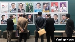 People stand in front of posters showing candidates for the presidential election in Seoul, South Korea