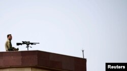 FILE - A sniper keeps a watch from the roof of the parliament building before Afghan President Ashraf Ghani arrives at the parliament in Kabul, Afghanistan, August 2, 2021.