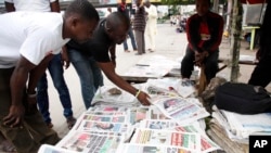 Men read newspapers on a street with headlines about Ebola virus killing a Liberian in Lagos, Nigeria, July 26, 2014. 