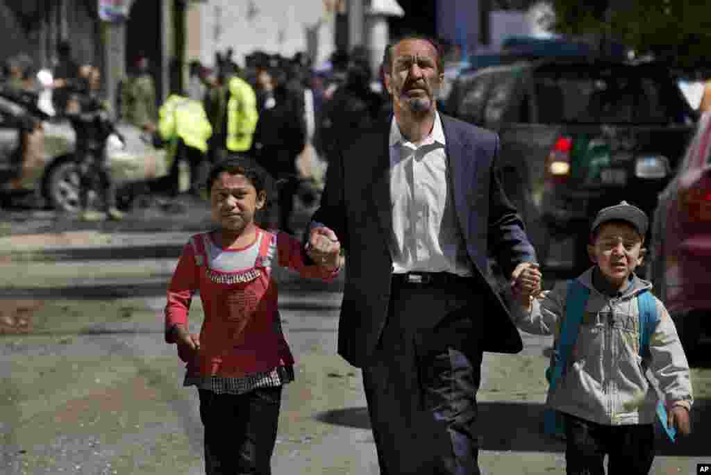 An Afghan man directs his children away from the scene where a suicide car bomber attacked a NATO convoy in Kabul, Afghanistan, May 16, 2013.