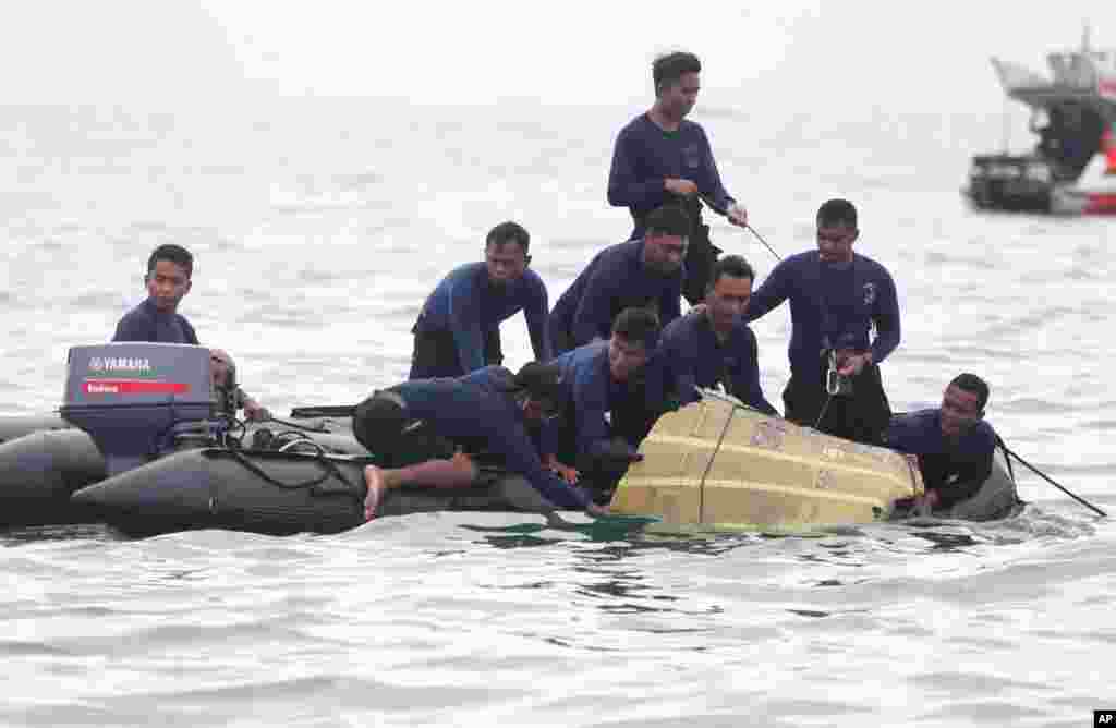Indonesian Navy divers pull out a part of an airplane out of the water during a search operation for the Sriwijaya Air passenger jet that crashed into the sea near Jakarta.