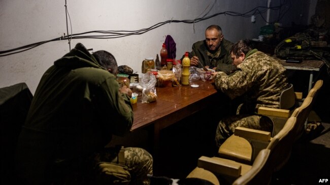 Ukrainian servicemen have lunch in their underground shelter in the frontline town of Bakhmut, in eastern Ukraine's Donetsk region on October 31, 2022. Since Russia's invasion of Ukraine, Bakhmut has been one of the most lethal battlefields for both sides.