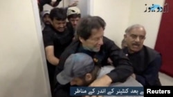 Former Pakistani Prime Minister Imran Khan is helped after he was reportedly shot in the shin, in Wazirabad, Pakistan, Nov. 3, 2022, in this still image obtained from video. (Urdu Media via Reuters)