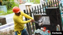 Un operario destruye la placa en una lápida que identifica al difunto como miembro de la Mara Salvatrucha en el cementerio de Santa Tecla, El Salvador, el 1 de noviembre de 2022.