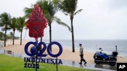 Seorang polisi berjalan melewati tanda G20 di Nusa Dua, Bali, 7 Juli 2022. Ketegangan di antara para anggota G20 menimbulkan kekhwatiran bahwa pelaksanaa KTT kali ini tidak akan menghasilkan komunike bersama. (AP/Dita Alangkara)