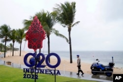 Seorang polisi berjalan melewati papan bertuliskan G20 di Nusa Dua, Bali, Kamis, 7 Juli 2022. (Foto: AP)