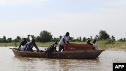 FILE: Mourners adjust a a casket on a pirogue while transporting it across floodwater to the Tukra cemetery in N'Djamena on October 29, 2022. - Chad is struggling to deal with exceptional flooding that has affected hundreds of thousands of lives.