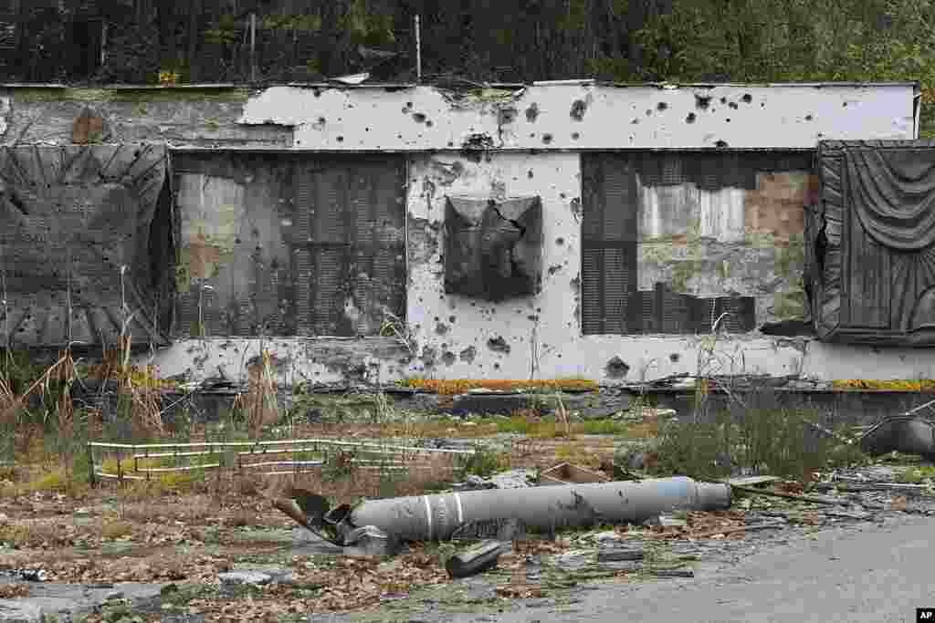 Part of a rocket lies in front of a WWII memorial damaged by fighting in the village of Dolyna, Donetsk region, Ukraine.
