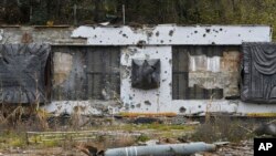 Part of a rocket lies in front of a WWII memorial damaged by fighting in the village of Dolyna, Donetsk region, Ukraine.