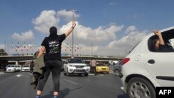 FILE - This UGC image posted on Twitter on Nov. 3, 2022, shows a person, wearing a shirt that translates from Persian to "We will fight, we will die, we will take back Iran," in the middle of a busy highway in the city of Karaj, Iran, near Tehran. 