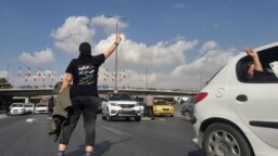 FILE - This UGC image posted on Twitter on Nov. 3, 2022, shows a person, wearing a shirt that translates from Persian to "We will fight, we will die, we will take back Iran," in the middle of a busy highway in the city of Karaj, Iran, near Tehran. 