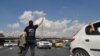 This UGC image posted on Twitter on Nov. 3, 2022, shows a person, wearing a shirt which translates from Persian to "We will fight, we will die, we will take back Iran," gesturing in the middle of a busy highway in the city of Karaj in the northern Alborz Province.