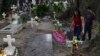 A couple walks next to one of the graves of gang members whose tombstone was destroyed on order of the government, during the Day of the Dead at the Nueva San Salvador Cemetery, in Santa Tecla, El Salvador, Nov. 2, 2022. 