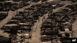 Two people walk along a road in a fire-ravaged community in the aftermath of the Palisades Fire in the Pacific Palisades neighborhood of Los Angeles, California, Jan. 13, 2025.