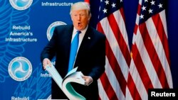 U.S. President Donald Trump pages through a document of U.S. government regulations before delivering remarks on regulatory relief at the Department of Transportation in Washington, June 9, 2017. 