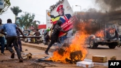 A supporter of Ugandan musician-turned-politician Robert Kyagulanyi, also known as Bobi Wine, carries his poster during a protest against the arrest of Kyagulanyi, during his campaign rally in Kampala, Uganda, Nov. 18, 2020. 