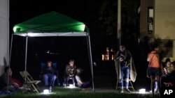 Vecinos al aire libre, utilizando carpas y luces portátiles por miedo a posibles réplicas, en su primera noche tras un terremoto de magnitud 6,4 en Guánica, Puerto Rico, el martes 7 de enero de 2020. (AP Foto/Carlos Giusti)