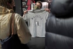 A person inside Rough Trade in Bristol, England, Dec. 11, 2021, holds up a T-shirt designed by street artist Banksy, being sold to support four people facing trial over the toppling of a statue of slave trader Edward Colston.