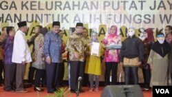 Gubernur Jawa Timur Soekarwo dan Walikota Surabaya Tri Rismaharini, mendampingi Menteri Sosial Salim Segaf Al Jufri, memberikan bantuan Buku Tabungan Secara Simbolis kepada PSK dan Mucikari Dolly dan Jarak di Surabaya, 19 Juni 2014 (Foto:VOA/Petrus)