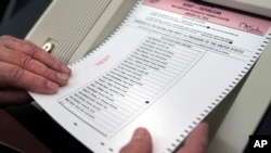 Nick Zaharias of Derry, New Hampshire, loads a test ballot into a vote-counting machine while testing machines before the New Hampshire primary, at the Derry Municipal Center, Jan. 16, 2024.