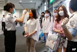 Passengers flying from Busan, South Korea, receive temperature checks for MERS (Middle East Respiratory Syndrome) as they arrive at Hong Kong Airport, June 5, 2015.