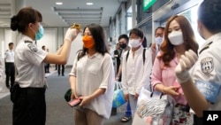 Passengers flying from Busan, South Korea, receive temperature checks for MERS (Middle East Respiratory Syndrome) as they arrive at Hong Kong Airport, June 5, 2015.