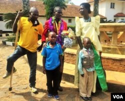 David Emong stands with family members after being received by the Ugandan Paralympic Sports Committee, the Ugandan Sports Council and numerous disabled athletes. (L. Paulat/VOA)