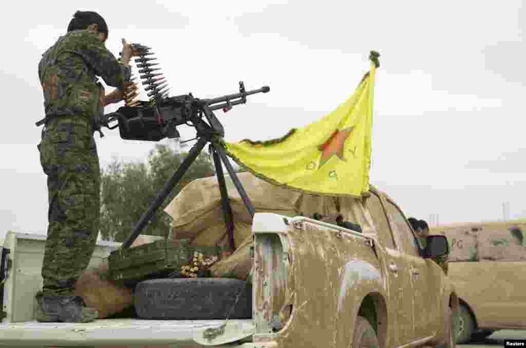 A Kurdish fighter is seen atop a pickup truck