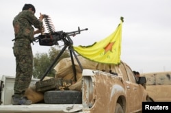 FILE - A Kurdish fighter is seen atop a pickup truck near the city of Ras al-Ain, Syria, November 5, 2013.