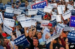 Audience members hold up signs supporting Republican presidential candidate Donald Trump during a campaign rally in Boca Raton, Florida, March 13, 2016.