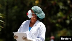 A doctor wearing a face mask speaks to a resident during a door-to-door verification of people to find out if they have developed any coronavirus disease (COVID-19) symptoms, in Nizaumuddin area of New Delhi, India, April 8, 2020. 