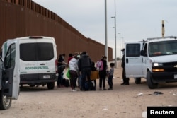 FILE - Migrants seeking asylum in the U.S. are being processed by the U.S. border patrol after crossing the border from Mexico at Yuma, Arizona, Jan. 22, 2022.