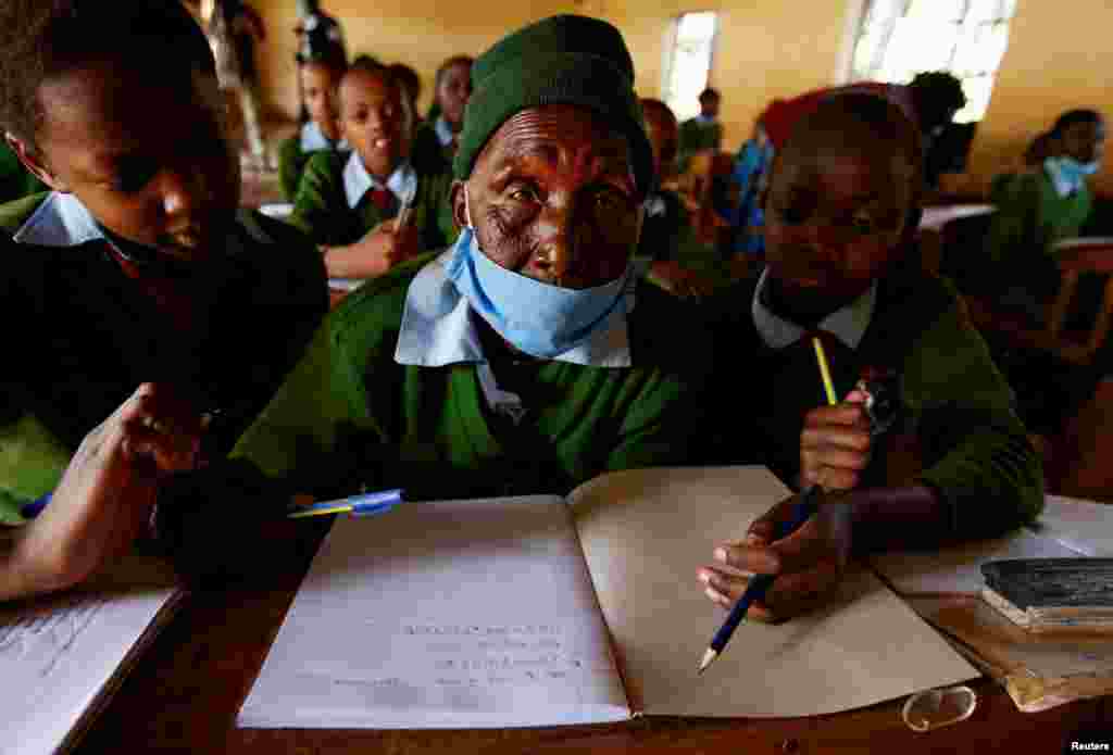 Priscilla Sitienei, a 98-year-old primary school student in grade six, is helped to do an assignment by her classmates at the Leaders Vision Preparatory School in Ndalat village of Nandi County, Kenya.