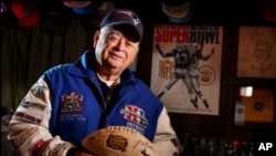 Donald Crisman poses with memorabilia from Super Bowls he has attended so far. Crisman, along with Tom Henschel, and Gregory Eaton have attended every Super Bowl since the first AFL-NFL World Championship held 55 years ago.