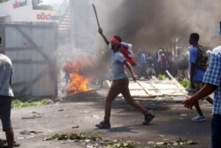 A masked protester wields a machete during a protest to demand the resignation of President Jovenel Moise in Port-au-Prince, Haiti, Sept. 27, 2019.