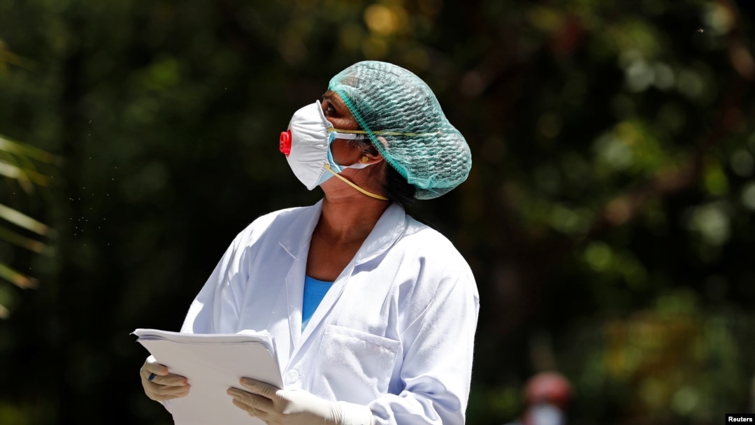 A doctor wearing a face mask speaks to a resident during a door-to-door verification of people to find out if they have developed any coronavirus disease (COVID-19) symptoms, in Nizaumuddin area of New Delhi, India, April 8, 2020. 