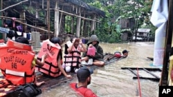 Sejumlah petugas penjaga pantai Filipina mengevakuasi warga di wilayah Panitan, Pulau Panai, yang terdampak oleh banjir yang melanda negara tersebut, pada 12 april 2022. (Foto: Philippine Coast Guard via AP)