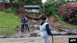 Des habitants se tiennent à côté d'un talus qui s'est effondré à la suite de fortes pluies en Nouvelle-Allemagne, près de Durban, en Afrique du Sud, le 12 avril 2022.