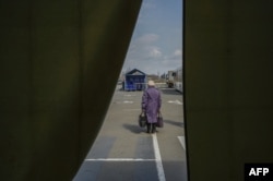 A woman stands outside of a tent after her arrival at a displaced persons' hub in Zaporizhzhia, some 200 kilometers (124 miles) northwest of Mariupol, on April 5, 2022.