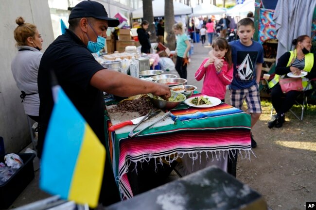 Mexican volunteer Felix Lara prepares tacos for Ukrainians refugees at a makeshift camp near the border, Monday, April 4, 2022, in Tijuana, Mexico. (AP Photo/Gregory Bull)