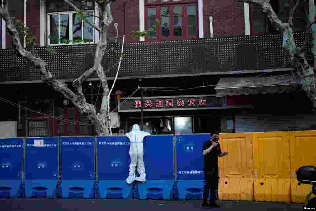 A person in a protective suit looks over barricades during a lockdown to curb the spread of the COVID-19 in Shanghai, China.